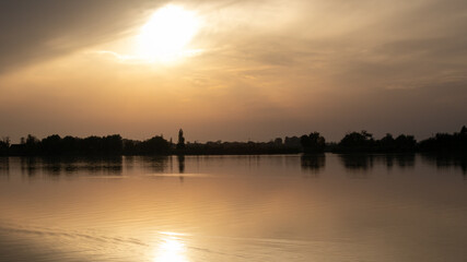 Serene sunset over a calm lake with silhouetted trees, evoking tranquility and reflection, perfect for meditation concepts