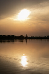 Fototapeta premium Serene sunset over a tranquil lake reflecting golden hues, symbolizing peace and introspection, perfect for relaxation themes