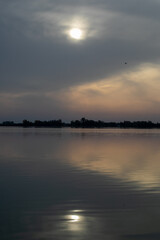Tranquil lakeside sunset with cloudy sky reflecting on water, capturing peacefulness and introspection, ideal for nature-themed relaxation concepts