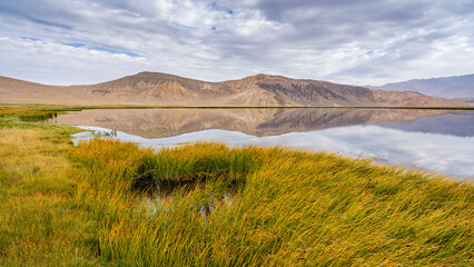 Scenic rural landscape view of Bulunkul lake with colorful mountains reflection, Murghab, Gorno-Badakhshan, Tajikistan
