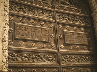 Intricately carved wooden door with Latin inscriptions.