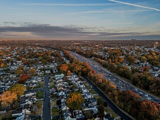 Fototapeta premium Aerial view of suburb with autumn colors and highway traffic.