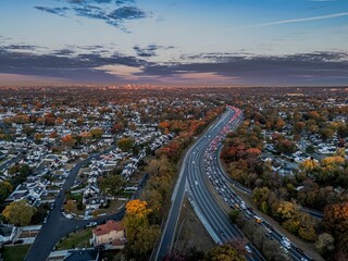 Fototapeta premium Suburban sunset with highway and city skyline.