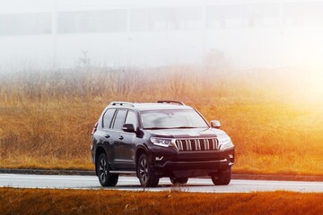 Fototapeta premium Elegant black SUV driving through scenic green countryside