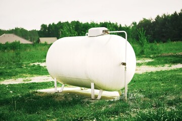 White propane tank in a grassy field powers a rural home, symbolizing independence and...