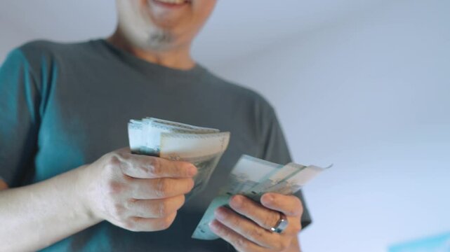 Man joyfully counting a stack of money while smiling