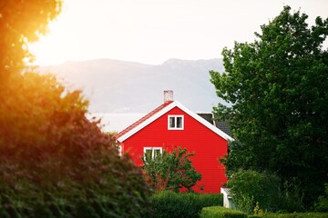 Fototapeta premium Red house by lake with mountains in background
