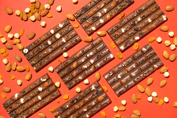 Lots of chocolate bars with nuts and raisins on a red background