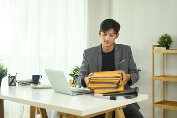 Young businessman organizing important documents in envelopes at office desk
