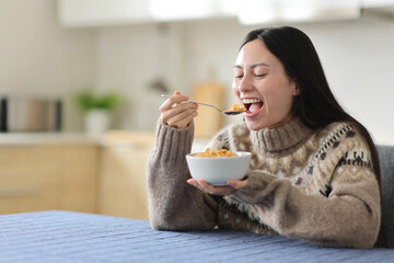 Happy asian woman eating cereals in a kitchen in winter