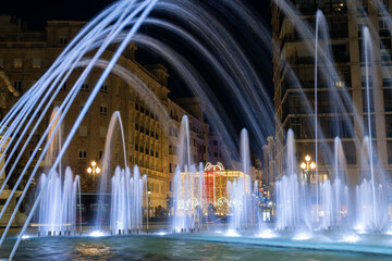 Caños de agua en la fuente de la plaza Zorrilla y luces de navidad en la ciudad de Valladolid,...