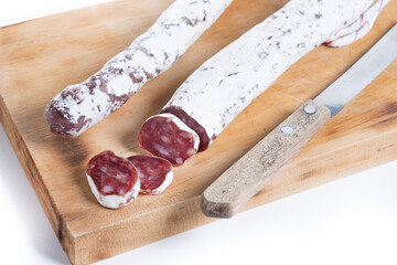 Fuet.Dry cured fuet sausage on wooden table isolated on white background