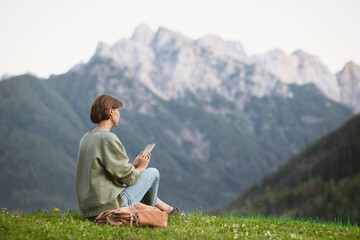 Young woman traveler using smartphone in Alps mountains. Travel and active lifestyle concept.