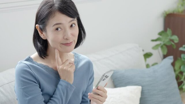 スマホを持って考えるミドル女性