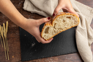 A rustic loaf of bread with slices is displayed on a dark slate board, accompanied by wheat stalks...