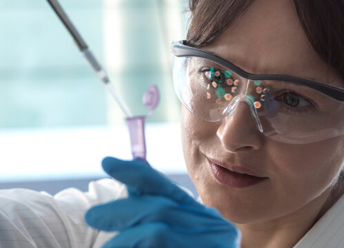 Smiling scientist putting medical sample into vial with pipette