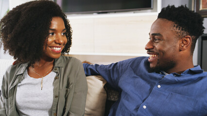 Happy, conversation and black couple on sofa in home for connection, bonding and date in lounge. Smile, talk and African man and woman relax in conversation for relationship communication in house.