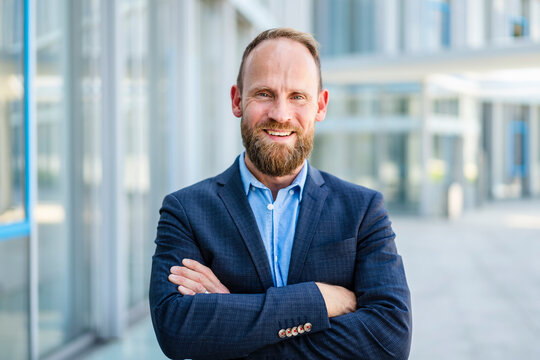 Confident businessman standing in office building with arms crossed