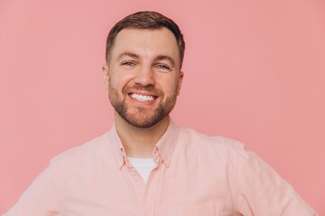 Cute smiling unshaven man in pink shirt posing isolated on pink background