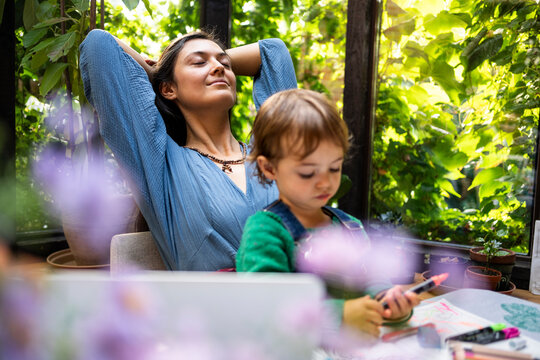 Smiling woman relaxing with son drawing in book at table
