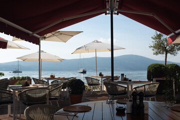 Seaside Restaurant Terrace with Mountain and Ocean View, Umbrellas, and Outdoor Dining Tables. High quality photo