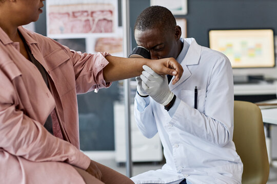 Portrait of senior African American doctor using dermascope while inspecting skin of patient during examination in clinic copy space