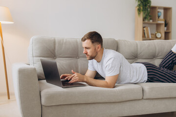 One man Caucasian male freelancer working from home with headphones on laptop computer customer...
