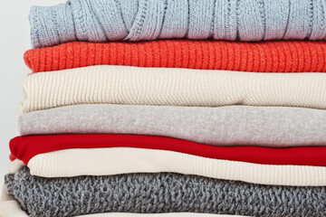Stack of sweaters in the winter, with a snowy. Stack fashion clothing concept. A w in white and white clothes warms up in winter with a sweater. Stack of clothes in winter with sweaters white and and.
