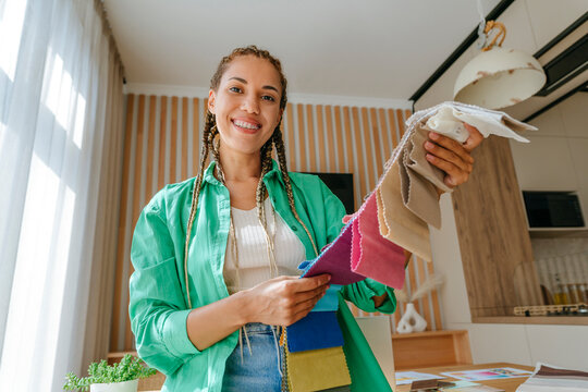 Smiling young fashion designer with fabric swatches at home - Powered by Adobe