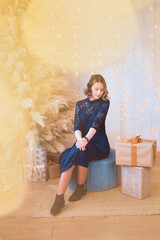 teenage girl in a dress near an unconventional Christmas tree surrounded by golden lights