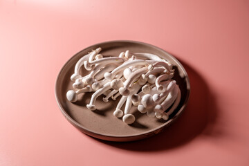 shimeji mushrooms on the plate, on pink, peach fuzz background