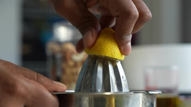 Squeezing of lemon using a manual steel squeezer by a man.