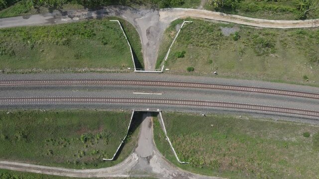 drone shot, double track railway with left and right rural rice fields. There is a tunnel for land vehicle passage.