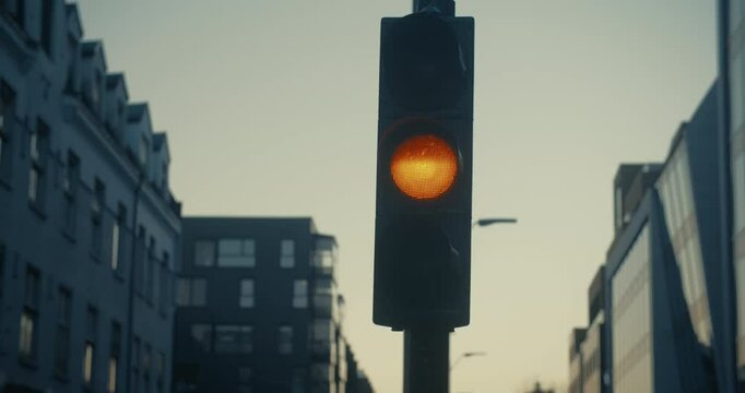 Low light cinematic shot of traffic light for cars changing light from green to yellow to red.
