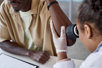 Detail shot of dermatologist examining skin using dermascope during patient check up in clinic copy...