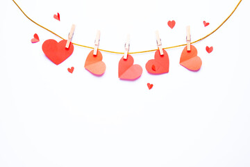A string of paper hearts hanging on wooden clothespins