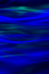 Defocused abstract green and blue background of speed camera movement over glowing lights. A pattern of flashes of light similar to the northern lights