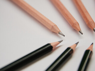 白い紙と緑色と木の色の鉛筆が並んでいる様子