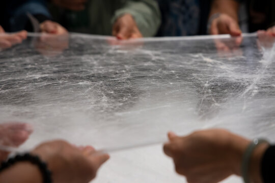 Woman stretching silk cocoon after soaking in hot water to loosen sericin gum. Suzhou silk factory, China