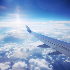 Fototapeta premium Aerial view from an airplane wing above fluffy clouds and a bright blue sky.