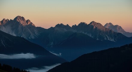 Breathtaking mountain range at sunrise with silhouetted peaks and misty valleys