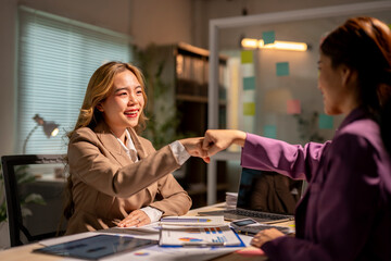 Two young businesswomen fist bumping after closing a business deal in the office