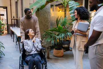 Diverse business team discussing in modern coworking space with plants and wheelchair user