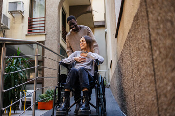 Young man pushing a disabled woman in a wheelchair on a ramp