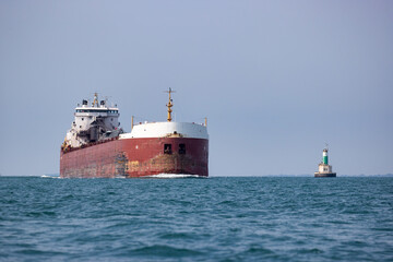 Cargo ship passing a lighthouse.