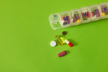Medicine, drugs and daily container in studio with healthcare routine, medical reminder and prescription. Pills, collection and tablets storage, management and treatment schedule on green background