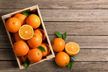 Top view of fresh oranges in wooden crate on wood planks.