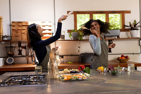 Two multiracial female friends cooking together in kitchen, preparing thanksgiving meal, at home