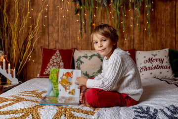 Sweet blond child, cute boy, playing with christmas toys on Christmas, beautifully decorated home for Christmas, cosy place