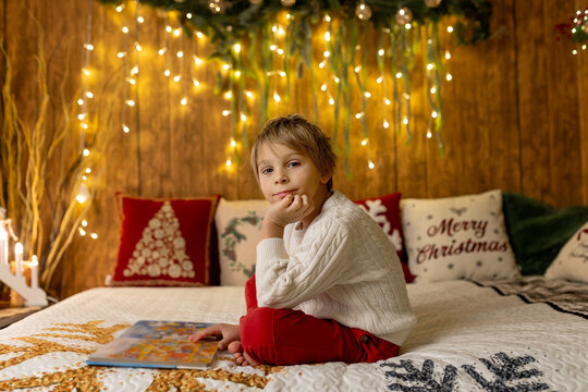 Sweet blond child, cute boy, playing with christmas toys on Christmas, beautifully decorated home for Christmas, cosy place